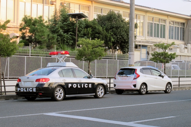 赤色灯を上げたパトカーと停車している車