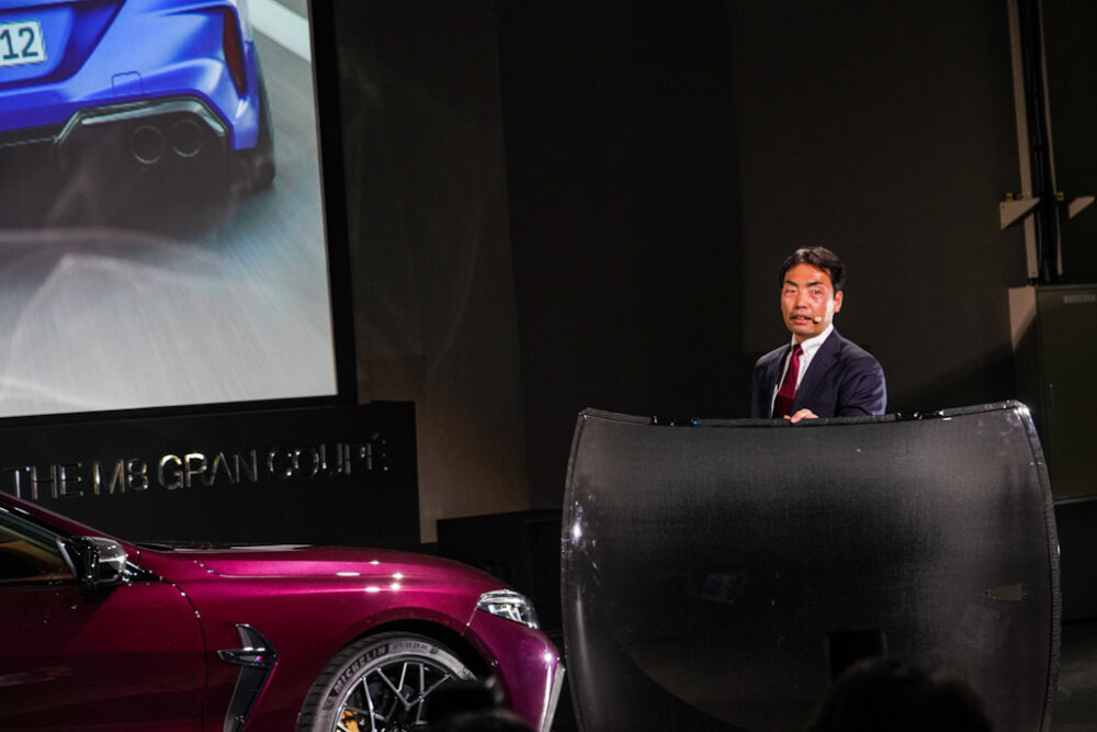 新型BMW M8 グラン クーペ の商品概要をプレゼンする、BMWブランド・マネジメント・ディビジョン プロダクト・マネージャー 御舘 康成氏。カーボンルーフ片手でひょいと持ち上げて見せる。