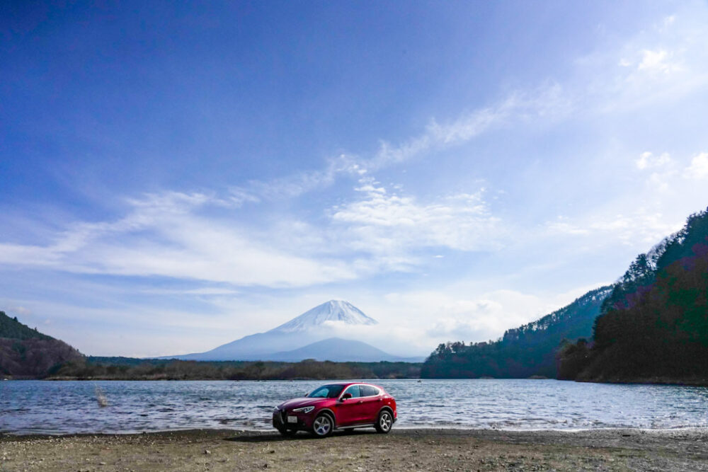 精進湖畔のほとりに停まるアルファロメオ・ステルヴィオ・2.2ターボディーゼル。背景は子抱き富士