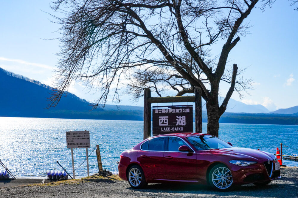 西湖を示す看板。背景は西湖。手前の車両はアルファロメオ・ジュリア・ターボディーゼル