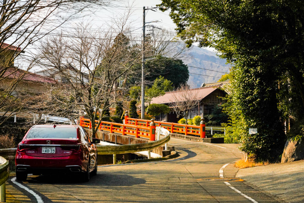 赤い欄干の橋の手前に停まるホンダ レジェンド