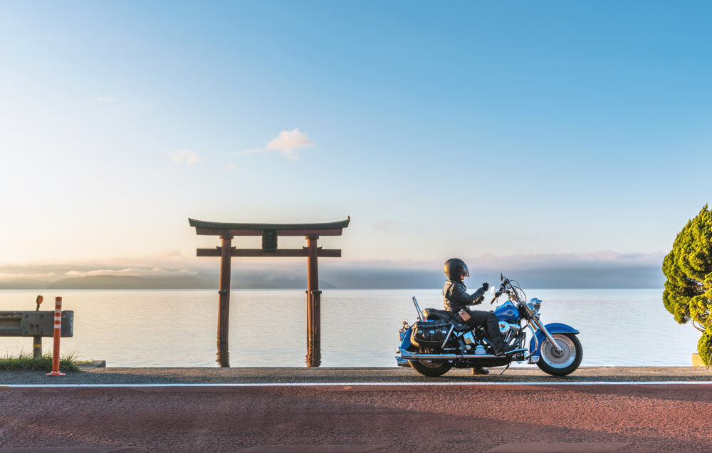 朝焼けの海岸を走るバイク