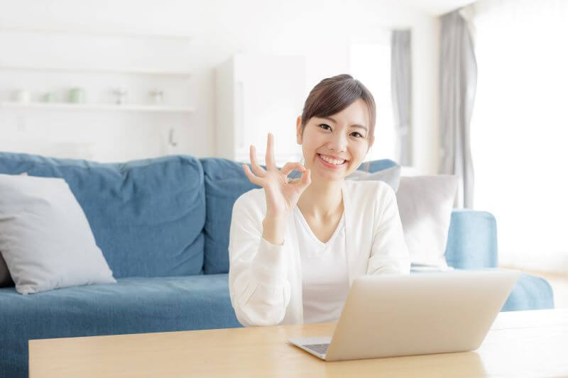 PCの前でOKサインをする女性