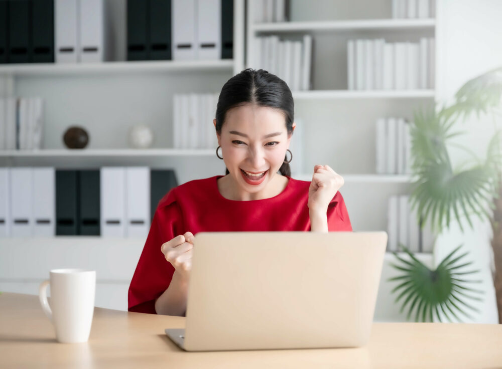 PCの前でガッツポーズをする女性