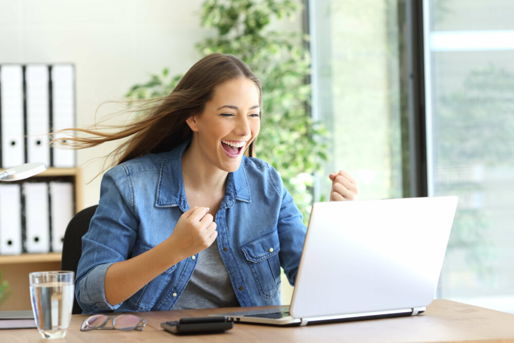 PC画面を見て喜ぶ女性